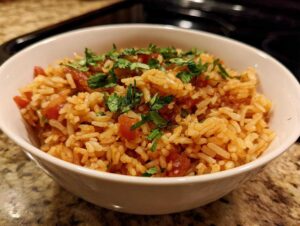 A close-up of a white bowl filled with delicious authentic Mexican rice, garnished with fresh cilantro.