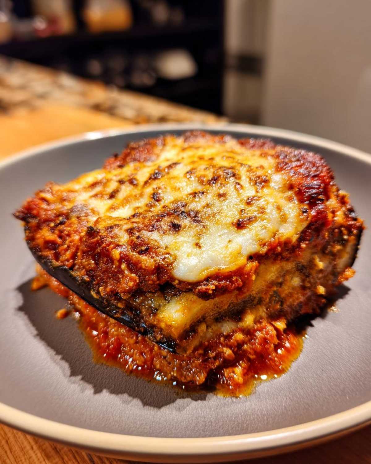 A close-up of a delicious slice of baked eggplant parmesan with melted cheese and marinara sauce.