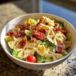 A bowl of creamy BLT pasta salad with farfalle pasta, crisp lettuce, cherry tomatoes, and crispy bacon.