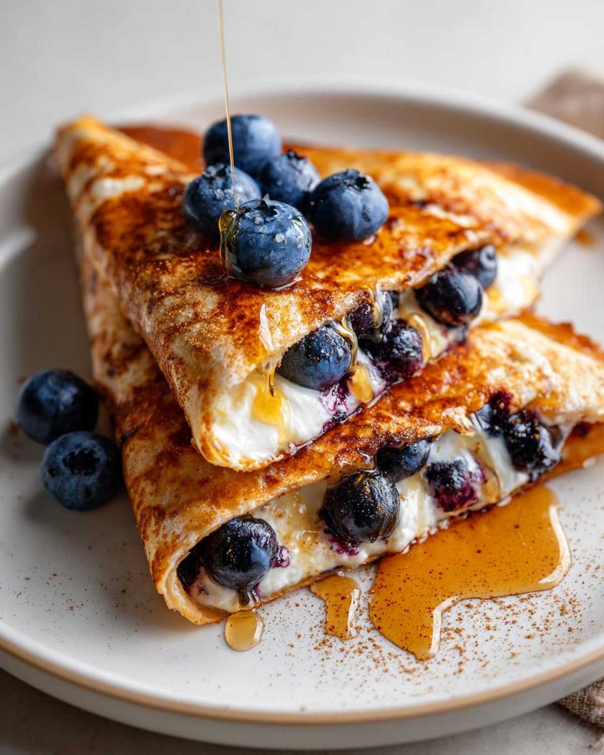 Close-up of a blueberry breakfast quesadilla folded in half, topped with fresh blueberries and drizzled with honey.