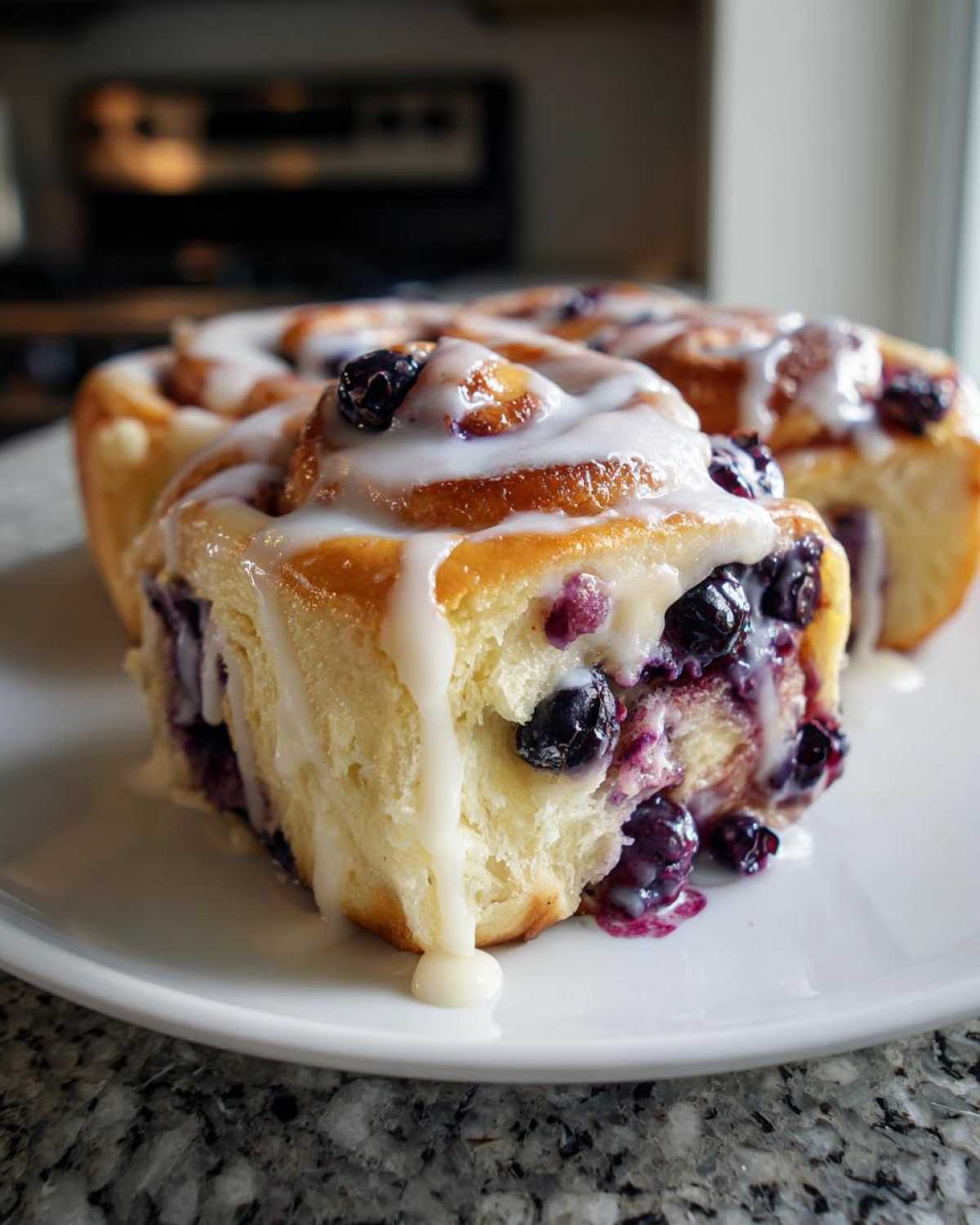 Close-up of delicious blueberry cheesecake rolls drizzled with white icing and fresh blueberries.