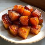 Close-up of glistening brown sugar roasted butternut squash cubes on a white plate.
