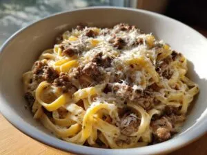 A bowl of creamy Cheeseburger Alfredo Pasta topped with seasoned ground beef and shredded Parmesan cheese.