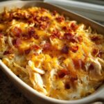 Close-up of a baked chicken bacon ranch casserole topped with melted cheddar cheese and crispy bacon bits.