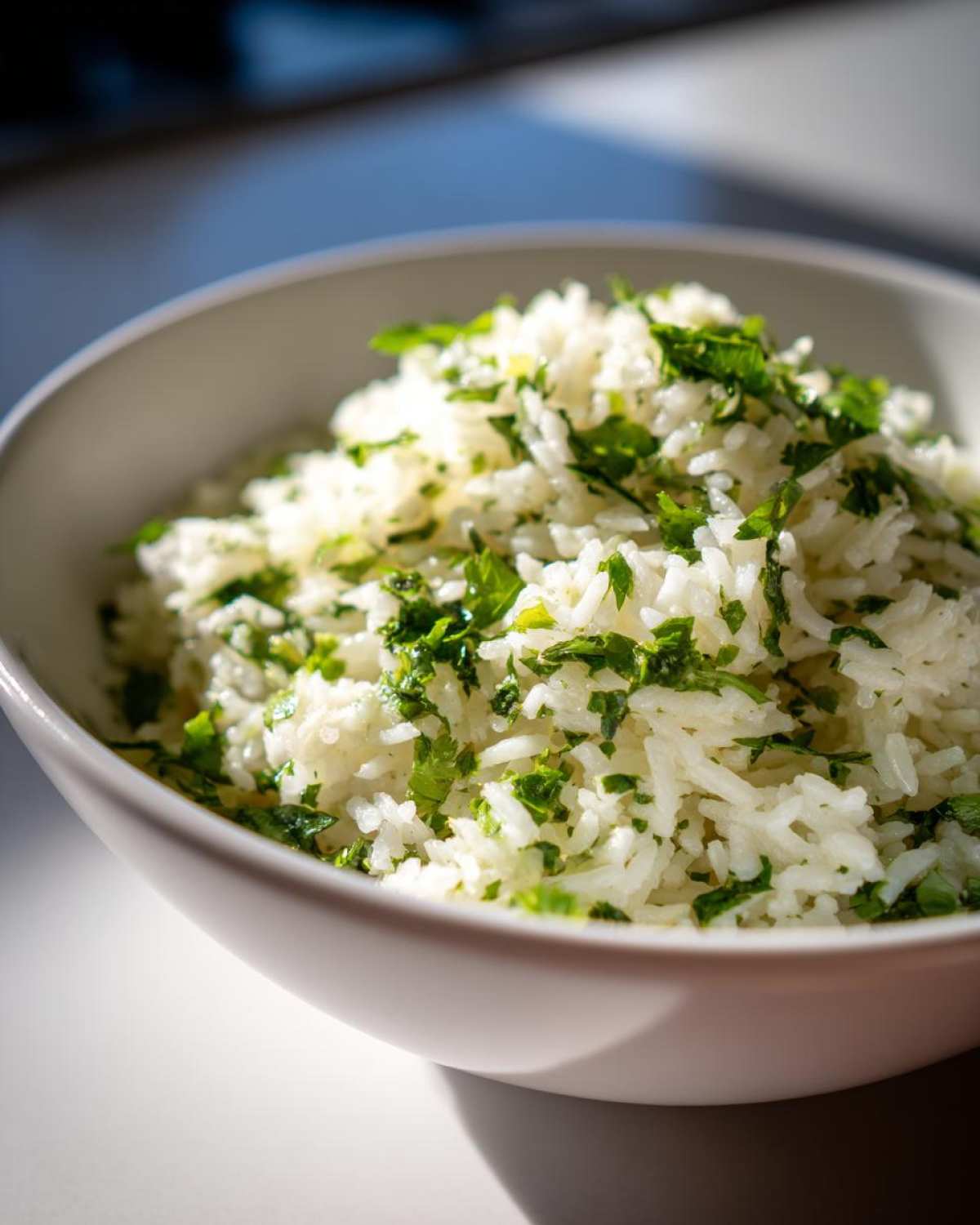 A close-up of fluffy cilantro lime rice in a white bowl, garnished with fresh green cilantro.