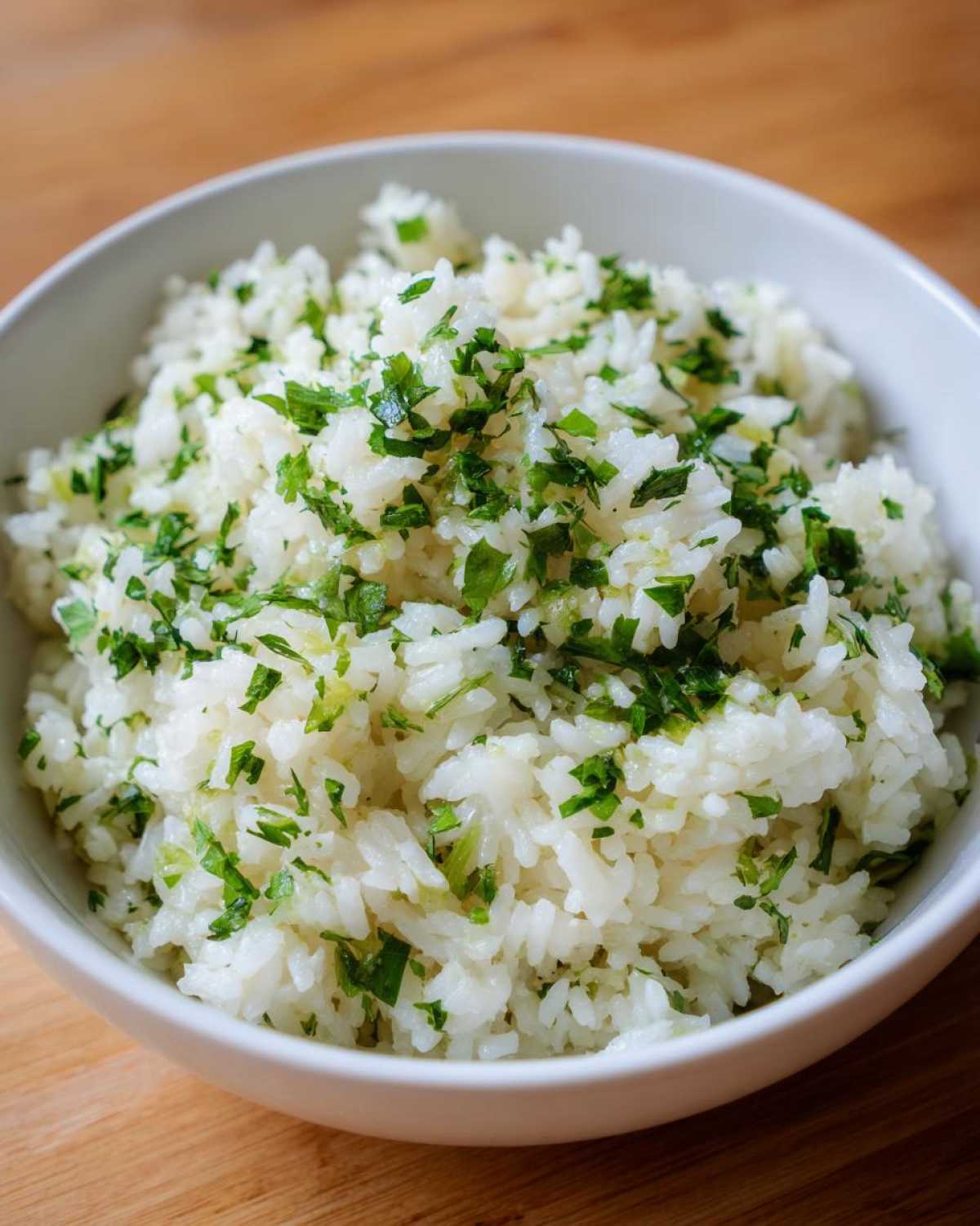 A close-up of fluffy cilantro lime rice in a white bowl, garnished with fresh chopped cilantro.