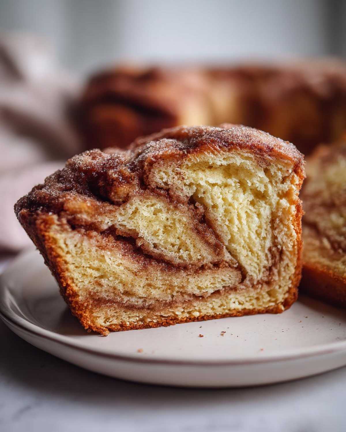 A close-up of a slice of cinnamon sugar bread, showing the swirled cinnamon filling and sugary topping.