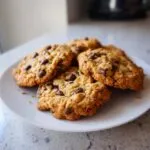 A pile of freshly baked classic chocolate chip cookies on a white plate.