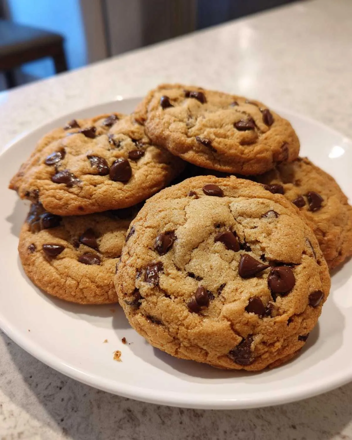 A stack of freshly baked classic chocolate chip cookies on a white plate.
