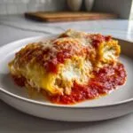A close-up of creamy cottage cheese lasagna roll ups smothered in marinara sauce and melted cheese.