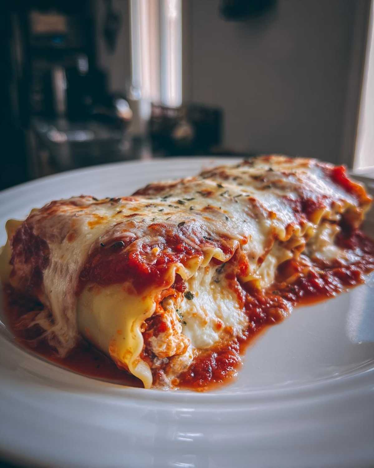A close-up of creamy cottage cheese lasagna roll ups covered in marinara sauce and melted mozzarella cheese.