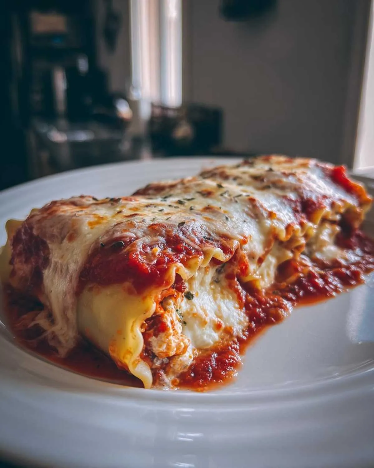 A close-up of creamy cottage cheese lasagna roll ups covered in marinara sauce and melted mozzarella cheese.