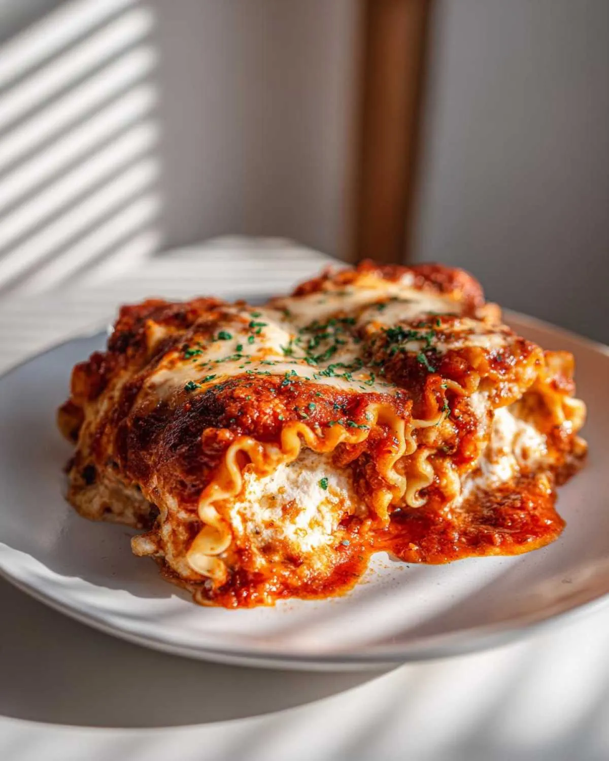 A close-up of creamy cottage cheese lasagna roll ups topped with marinara sauce and melted cheese, garnished with parsley.
