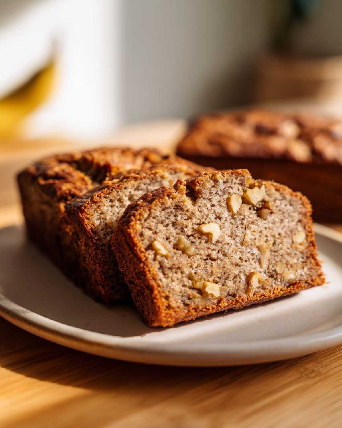 Close-up of sliced easy moist banana bread with visible walnuts on a plate.