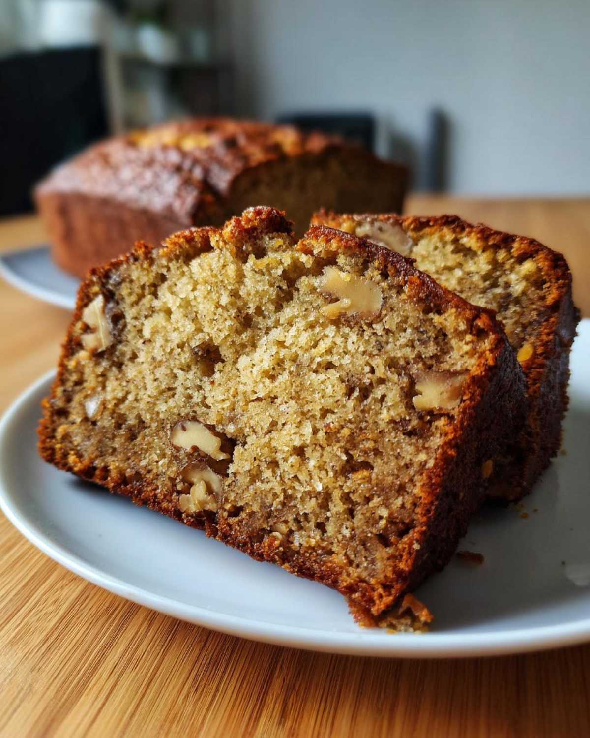 Close-up of two slices of easy moist banana bread with visible walnuts on a white plate.