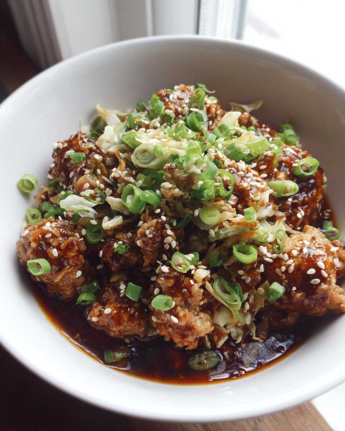A close-up of a bowl filled with Egg Roll in a Bowl, topped with sesame seeds and chopped green onions.