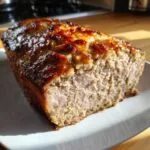 A close-up of a slice of juicy garlic butter turkey meatloaf on a white plate.