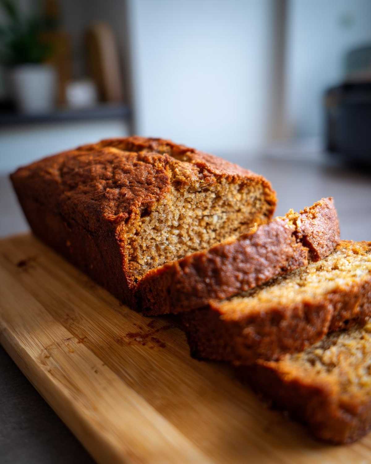 Close-up of three slices of Hawaiian banana bread on a wooden cutting board.
