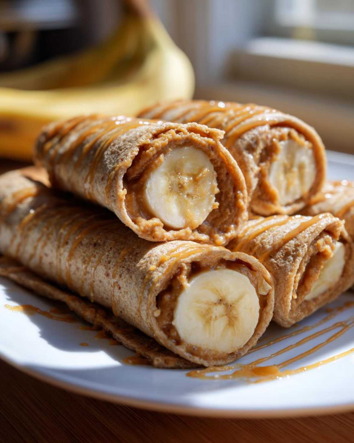 Close-up of high protein banana roll-ups filled with peanut butter and banana slices, drizzled with caramel.