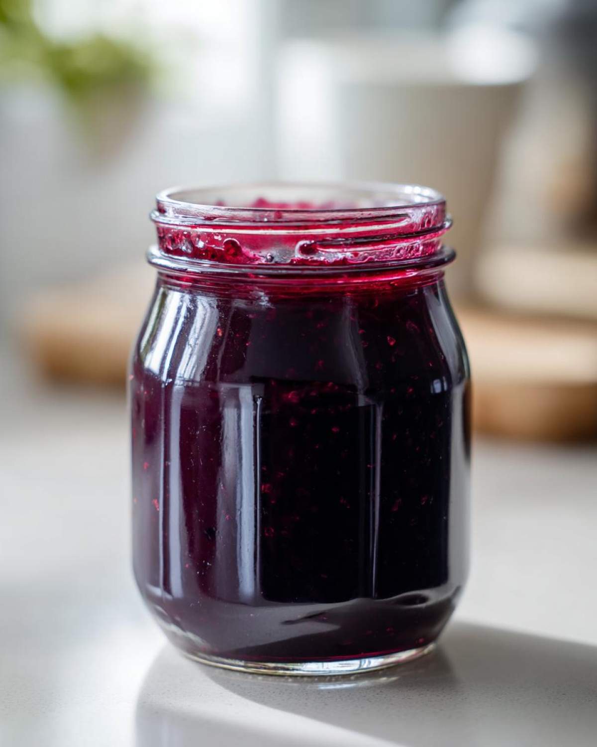 A close-up shot of a glass jar filled with glistening homemade grape jelly.