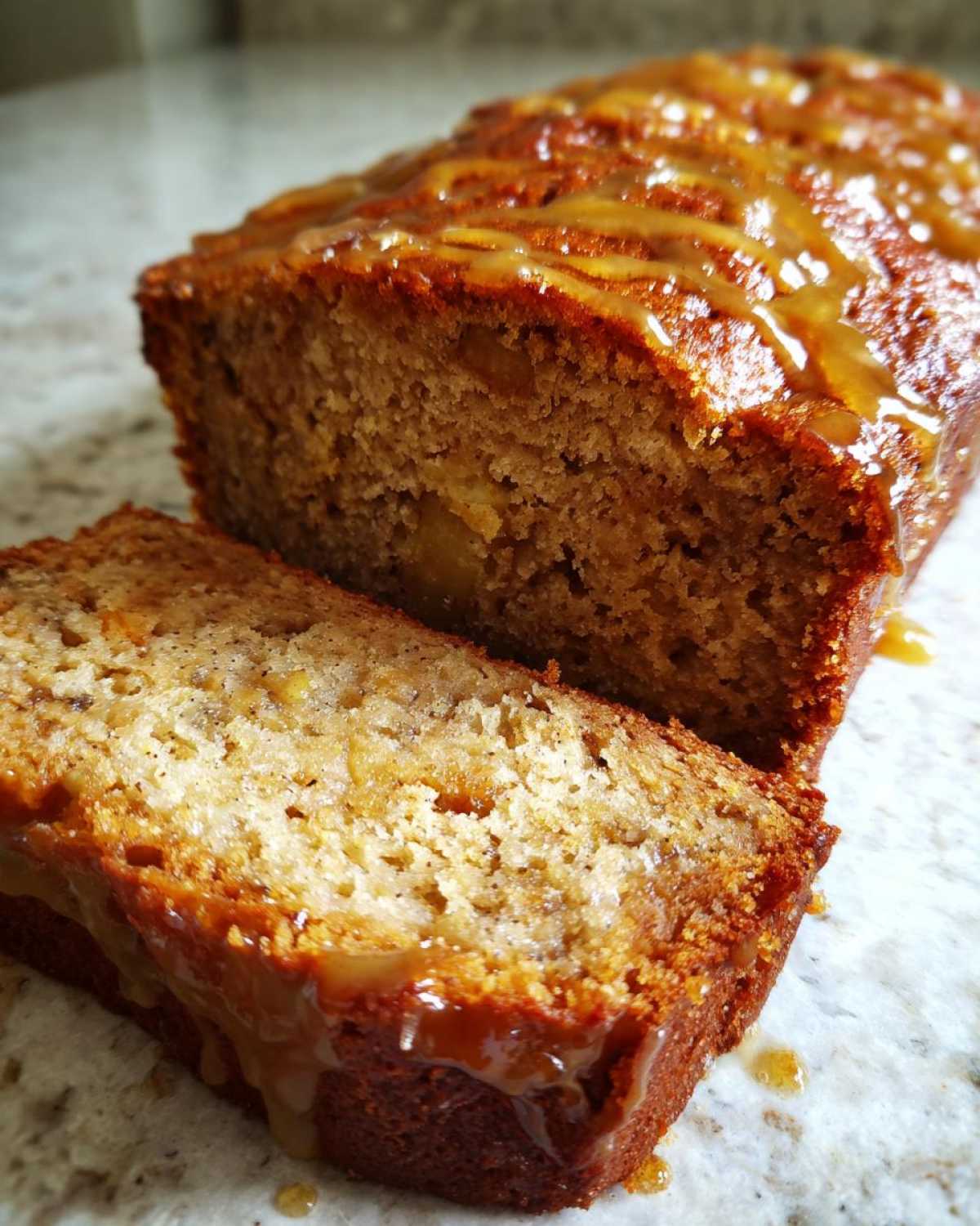 A close-up of a moist Honey Vanilla Banana Bread loaf, sliced and drizzled with a sweet glaze.