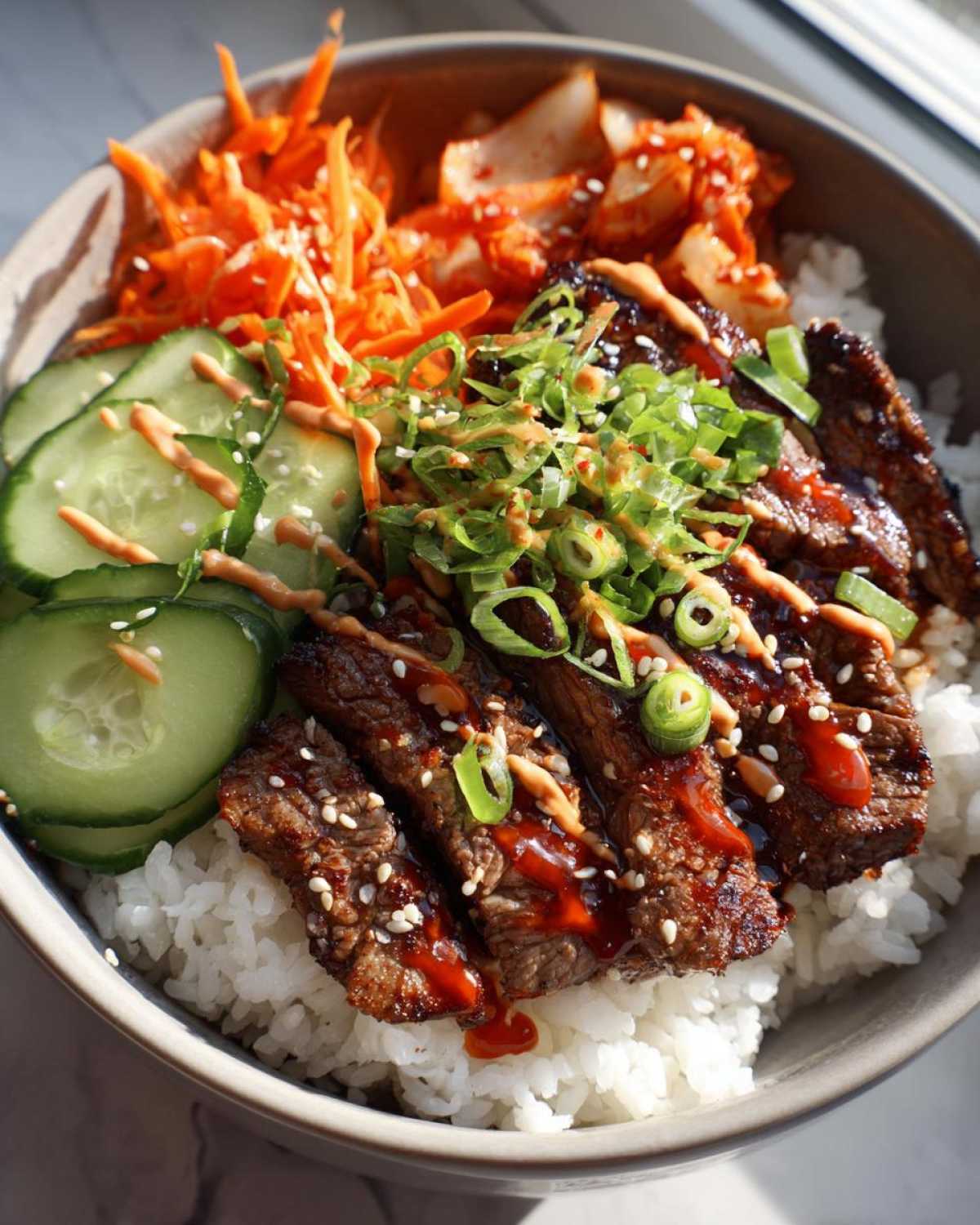 A close-up of Korean BBQ steak rice bowls, featuring sliced steak, rice, kimchi, shredded carrots, and cucumber slices.
