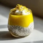 A refreshing glass of lemon cream chia pudding topped with whipped cream, lemon zest, and chia seeds.