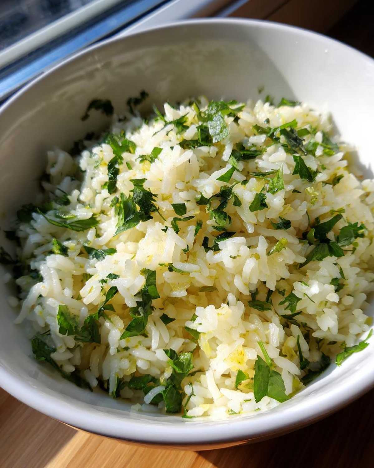 A close-up of fluffy Mediterranean lemon rice generously seasoned with fresh chopped parsley and lemon zest.