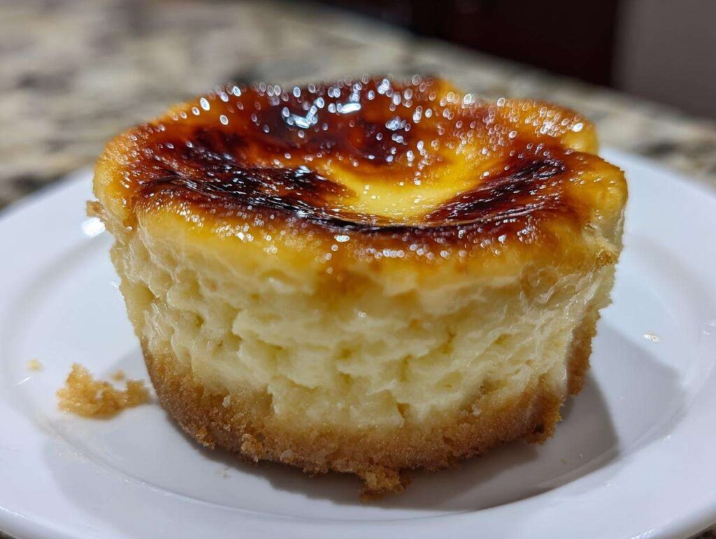Close-up of a single mini creme brulee cheesecake with a golden caramelized sugar topping and a graham cracker crust.