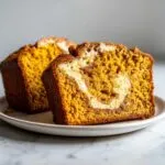 Close-up of a slice of moist pumpkin cream cheese bread with a beautiful cream cheese swirl.