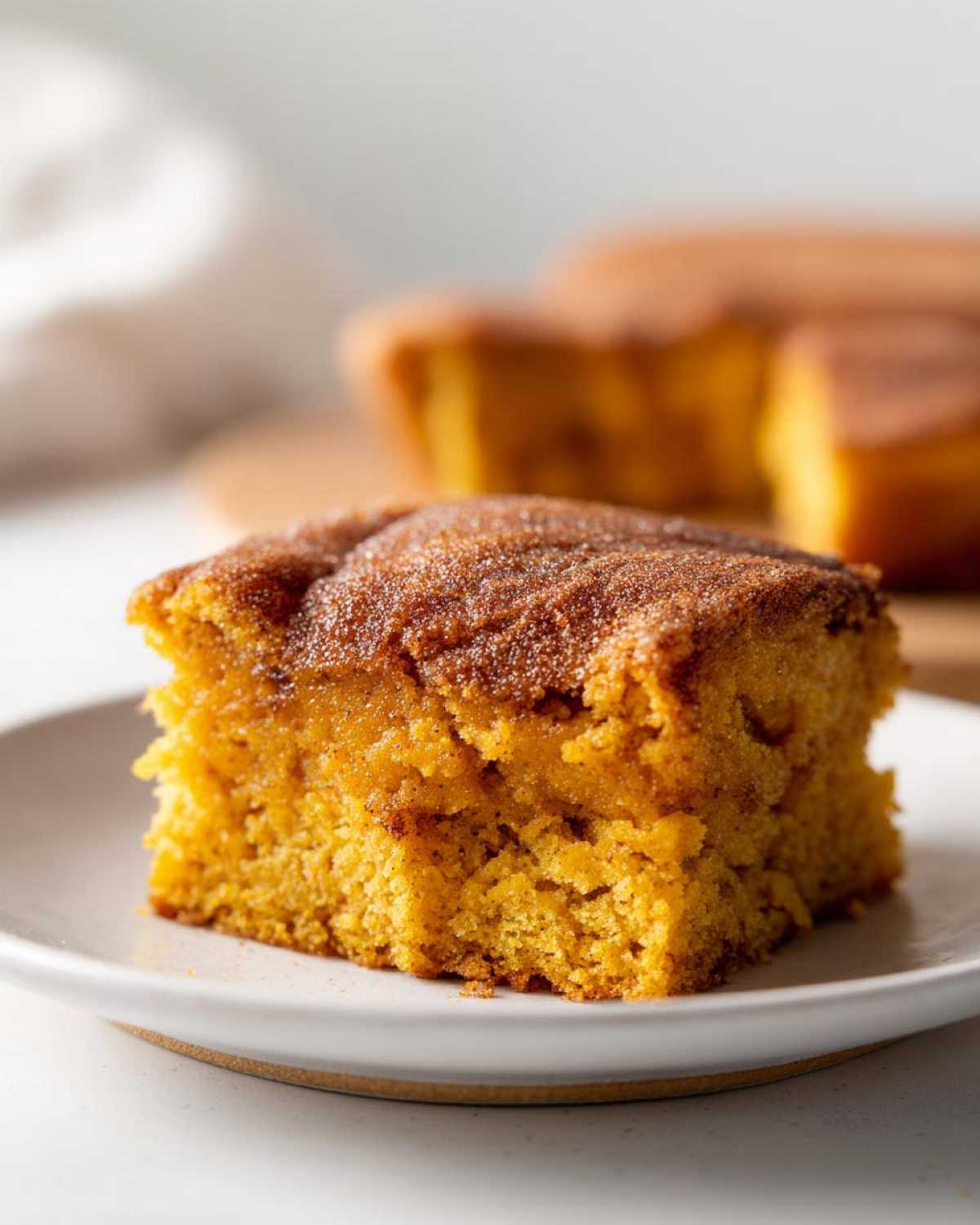 A close-up of a slice of pumpkin snickerdoodle snack cake with a cinnamon-sugar topping.