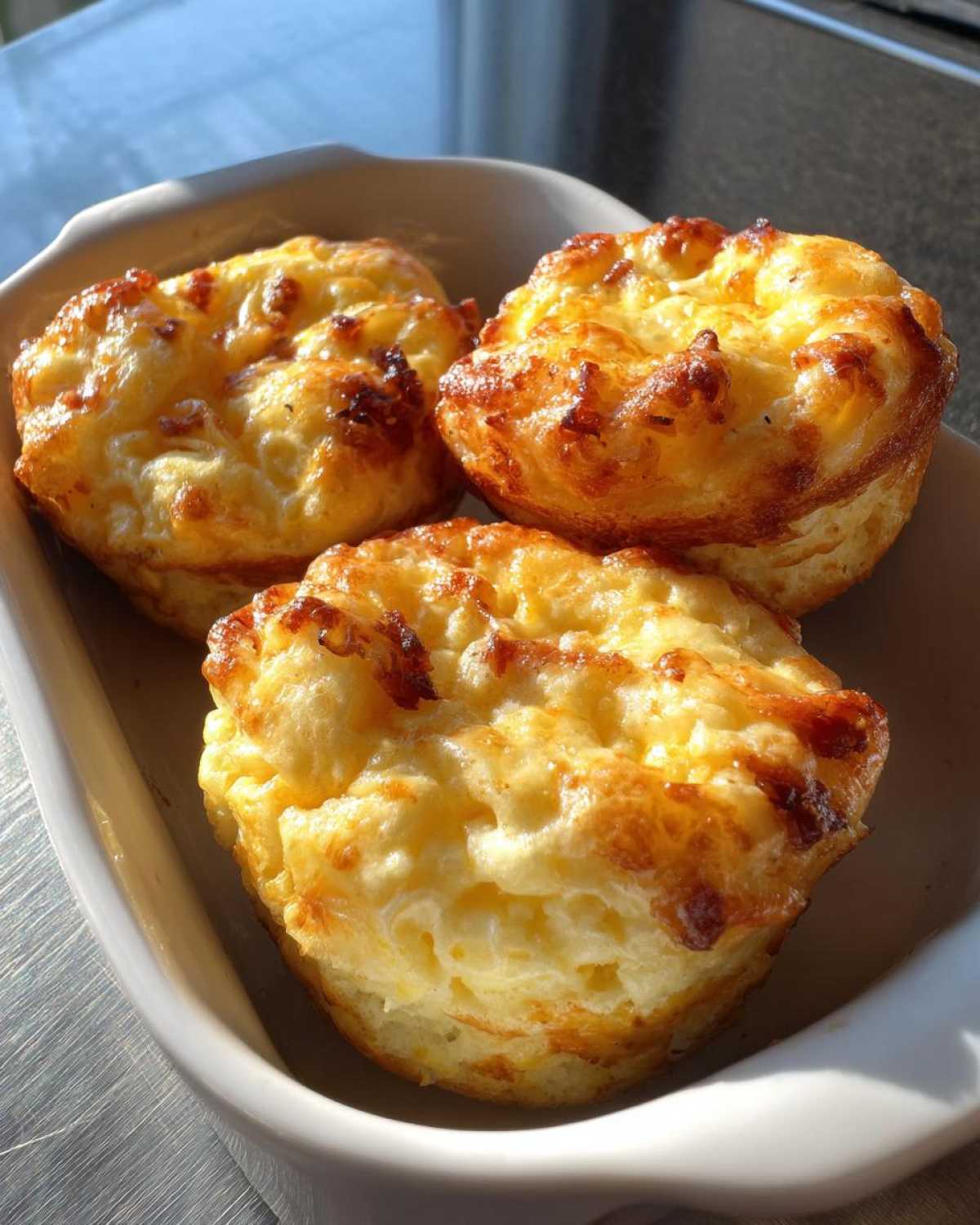 Three freshly baked Starbucks egg bites in a white dish, golden brown and fluffy.