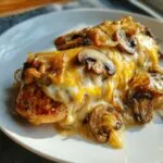 A close-up of Texas Roadhouse smothered chicken topped with melted cheese, sautéed mushrooms, and onions.