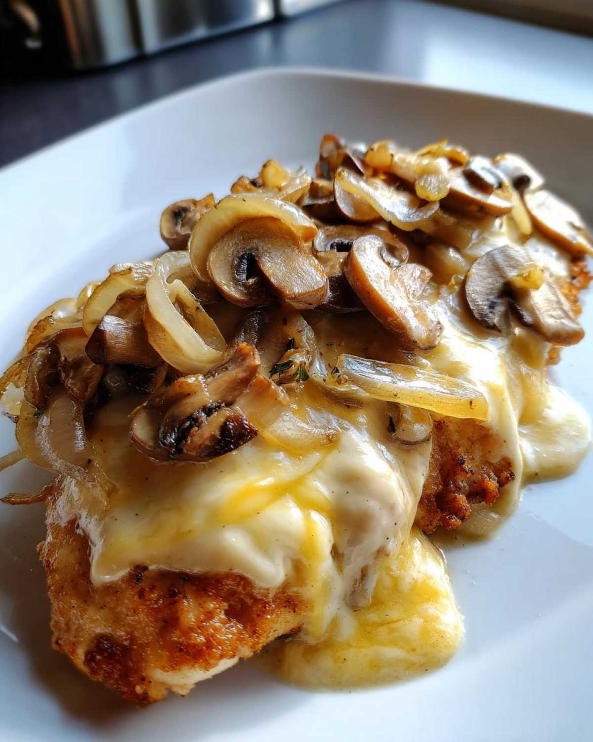 Close-up of Texas Roadhouse Smothered Chicken topped with melted cheese, sautéed mushrooms, and onions.