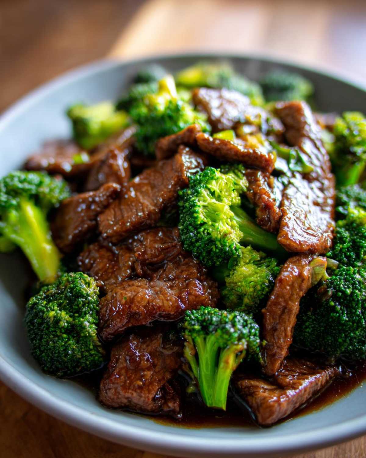 Close-up of a bowl filled with tender slices of beef and vibrant green broccoli florets in a glossy sauce.