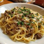 A close-up of a plate of Beef and Garlic Butter Linguine, topped with fresh parsley and grated cheese.