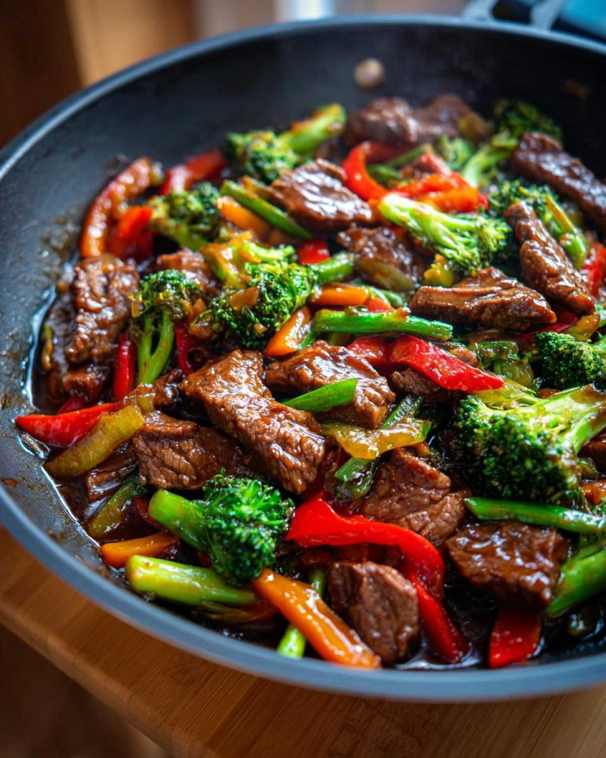 Close-up of a colorful beef stir fry with tender beef strips, broccoli florets, red bell peppers, and green beans in a glossy sauce.