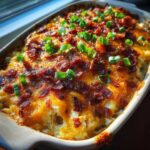 Close-up of a bubbling crack chicken casserole topped with melted cheese, crispy bacon, and green onions.