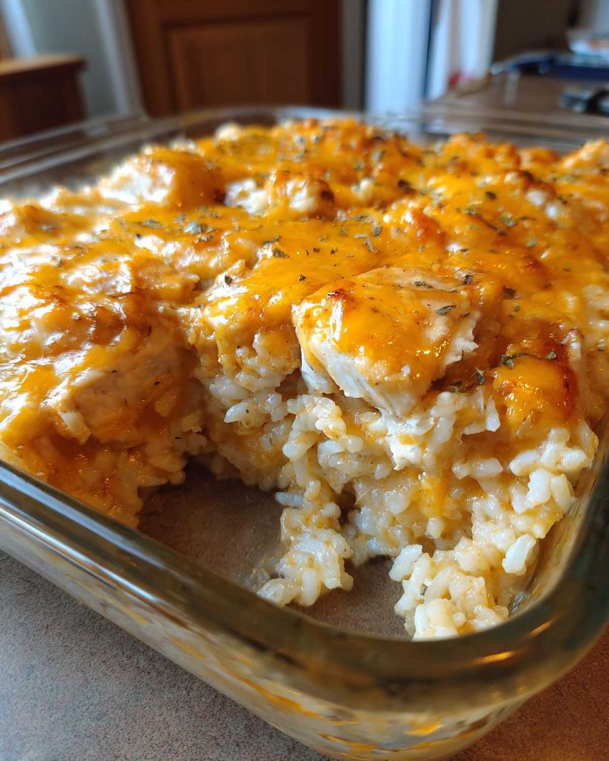 A close-up shot of a creamy chicken and rice casserole topped with melted cheddar cheese and herbs.