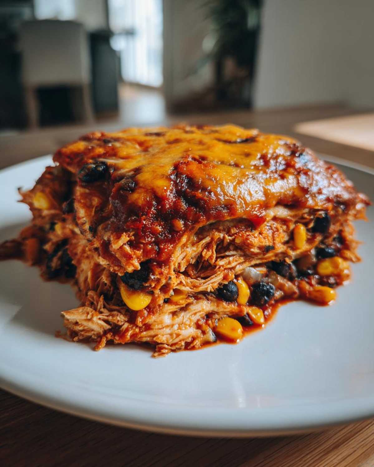 A hearty slice of crockpot chicken enchilada casserole with shredded chicken, black beans, corn, and melted cheese.