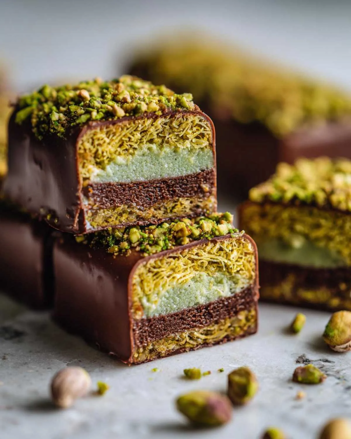 Close-up of decadent Dubai chocolate bars layered with crunchy pastry, pistachio cream, and chocolate ganache, topped with chopped pistachios.