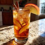 A refreshing Fall Long Island Iced Tea cocktail garnished with apple slices and cinnamon sticks, perfect for autumn.