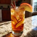 A refreshing Fall Long Island Iced Tea cocktail garnished with apple slices and cinnamon sticks, perfect for autumn.