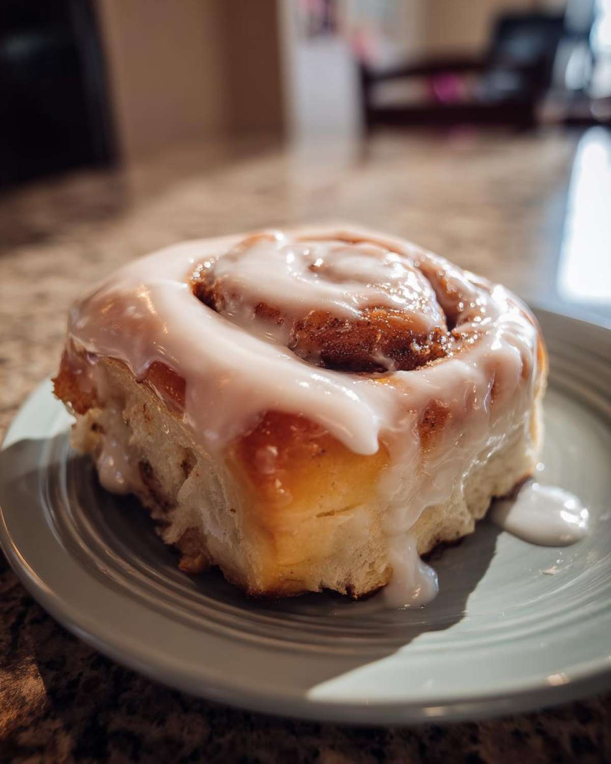 Close-up of a fluffy cinnamon roll generously topped with white icing, ready to be enjoyed.