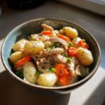 A close-up of a bowl filled with Gnocchi Chicken Pot Pie, featuring tender gnocchi, shredded chicken, peas, and carrots in a creamy sauce.