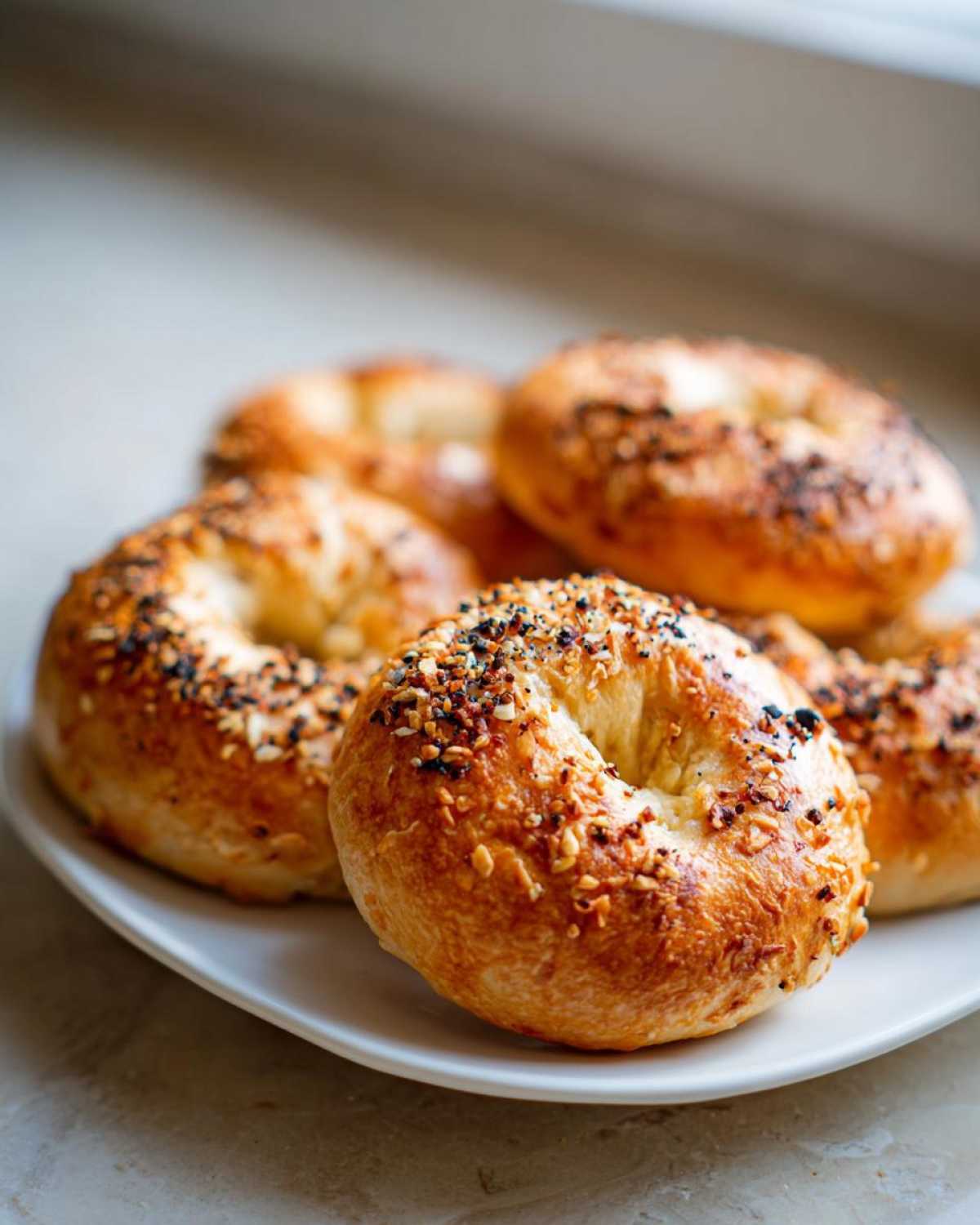 A plate of freshly baked Greek yogurt bagels topped with everything seasoning.