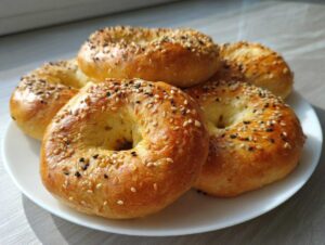 A plate piled high with golden-brown Greek yogurt bagels, generously topped with sesame and black sesame seeds.
