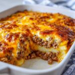 A close-up of a freshly baked hamburger potato casserole, featuring layers of ground beef and potatoes topped with bubbling, golden-brown melted cheese.