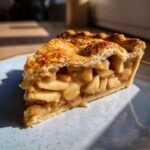 Close-up of a generous slice of homemade apple pie, showcasing a golden-brown lattice crust and tender apple filling.