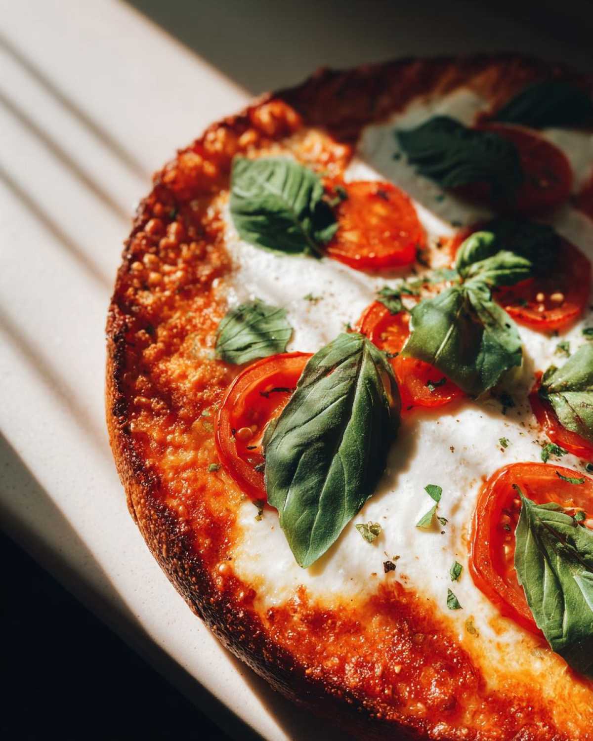 Close-up of a delicious Margherita pizza with melted mozzarella, fresh tomato slices, and basil leaves.